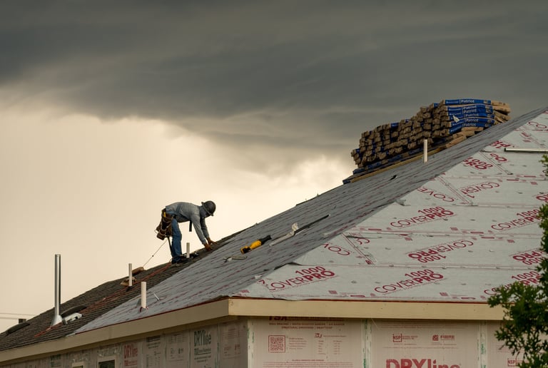Roofer installing shingles on roof of new home